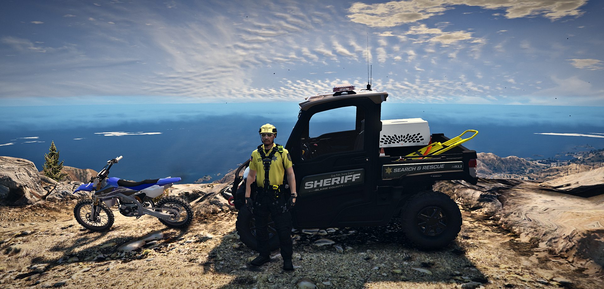 Agente del Search and Rescue con il fuoristrada dello sceriffo e una moto da cross in cima a una montagna sul mare